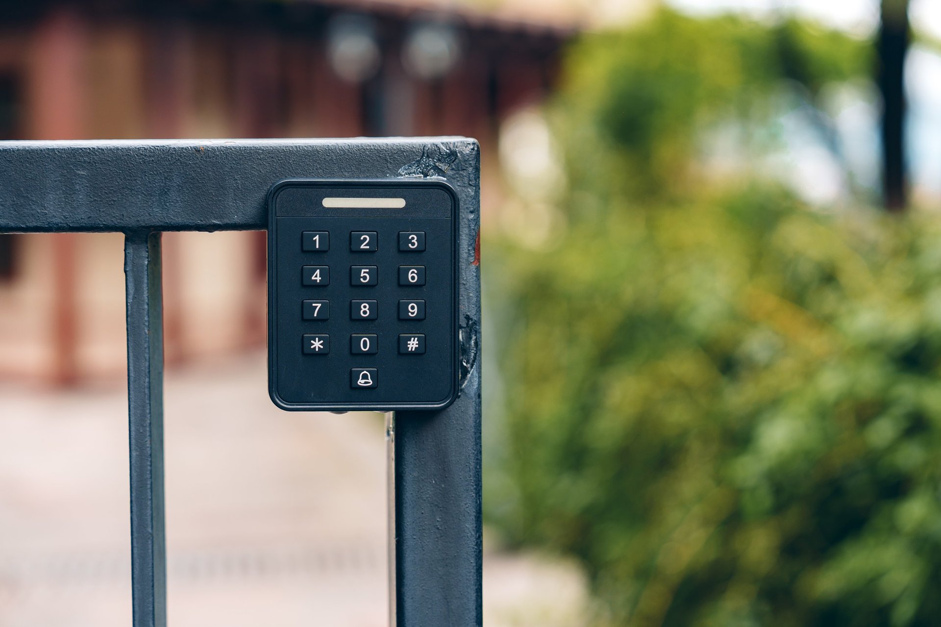 A keypad is installed on a metal gate in front of a building