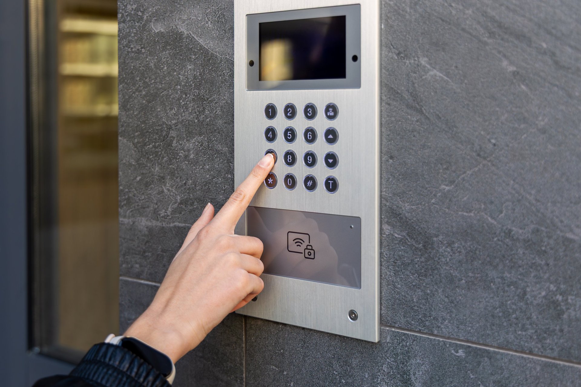 Hand pressing keypad on video intercom panel for secure building access
