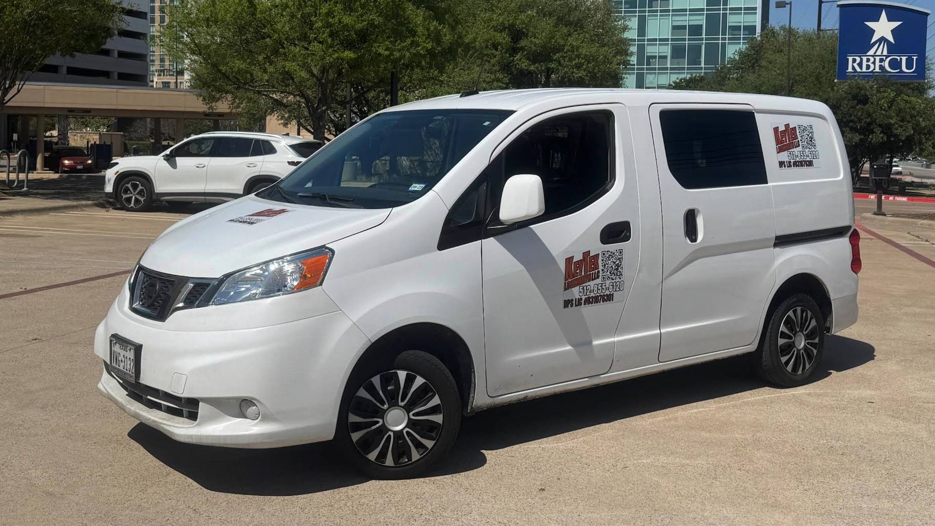 White Nissan NV200 compact commercial van with RBFCU branding parked in urban setting